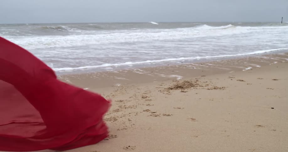 A red sheet blows in the wind on the beach