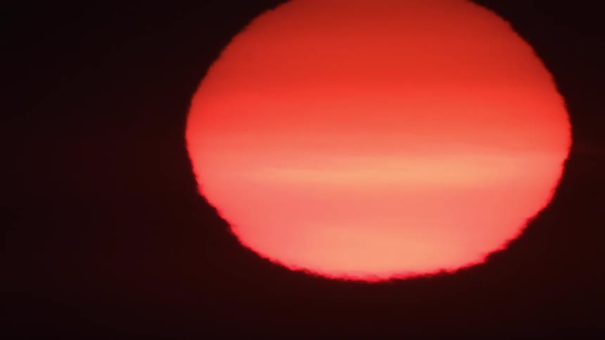 The bright red sun sets at dusk