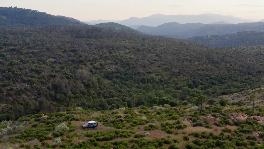 Aerial view of an all terrain vehicle on a hill near the mountains