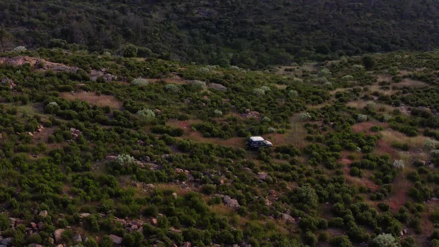 A vehicle driving across a field covered in bushes