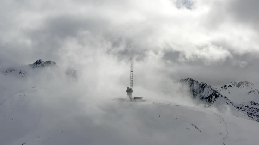 An aerial view of a mountain covered in snow is displayed