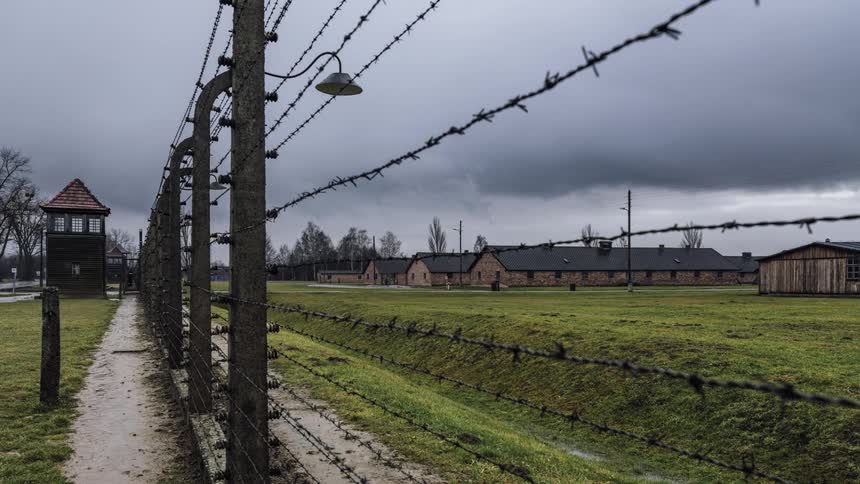 Dark clouds move over the green grass and the barbed wire fence