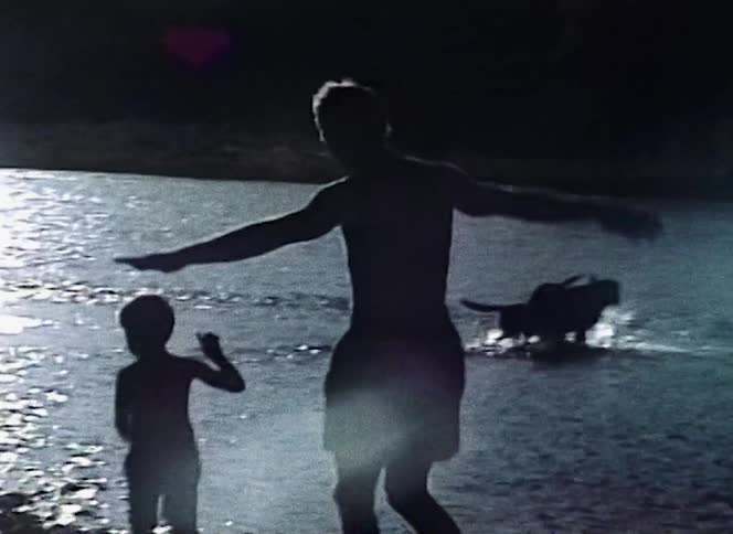 A woman and son are playing near a lake outdoors