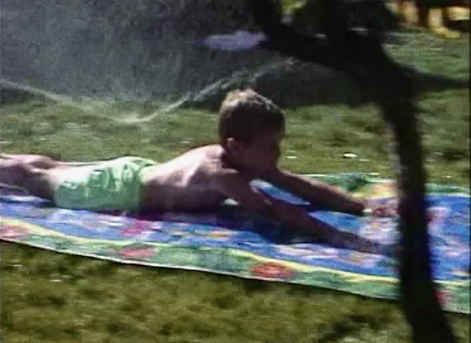 Little boy sliding across a slip in slide in the backyard