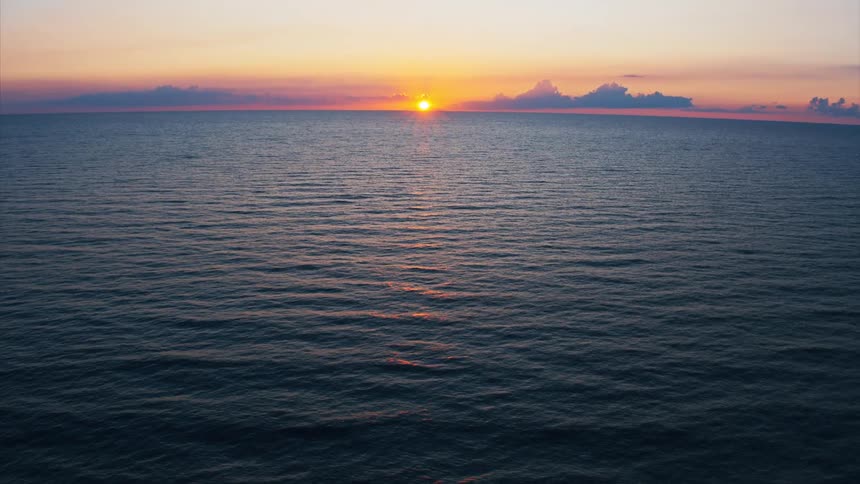 The sun glows on the horizon above the ocean