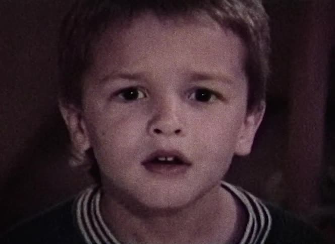 Boy stares surprised then smiles after briefly looking over shoulder