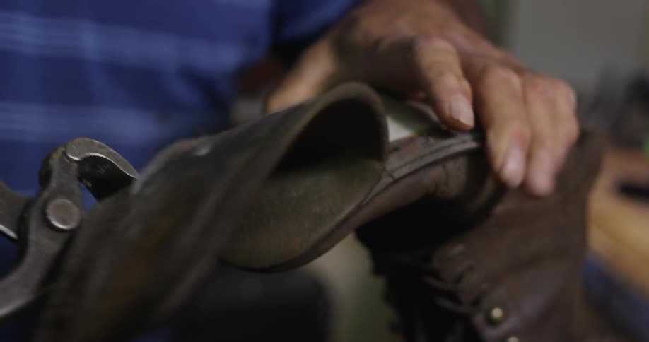 A man pulls the sole off of a boot