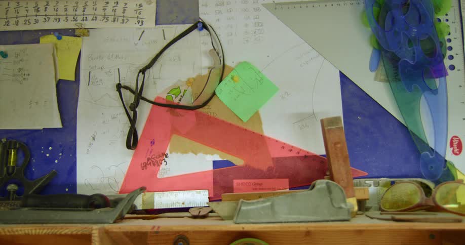 A bulletin board above a shelf in a classroom is covered with math tools and papers