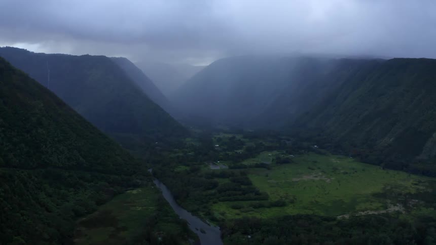 An aerial view of fog over a hills with a river running through the valley