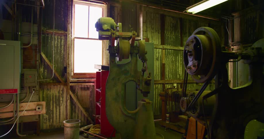 Machinery stands idle in empty workshop set in metal walled building