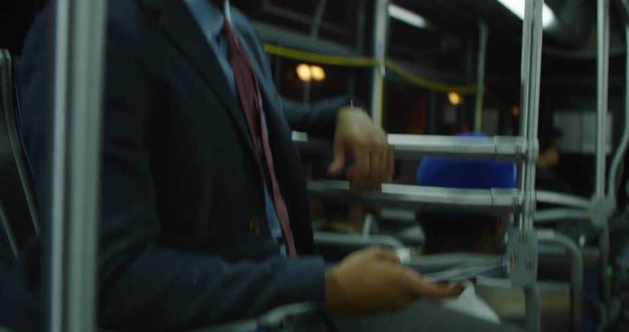 A man sitting on a subway pulls out his phone