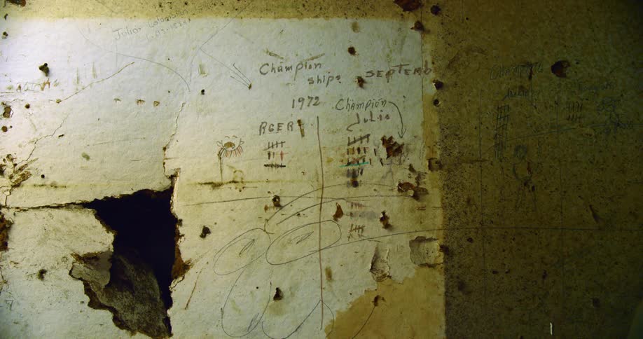 A wall with a hole in it with pen marks writing and drawings