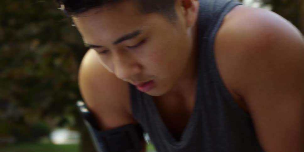 Asian tired man with his hands on knees breathing in and out