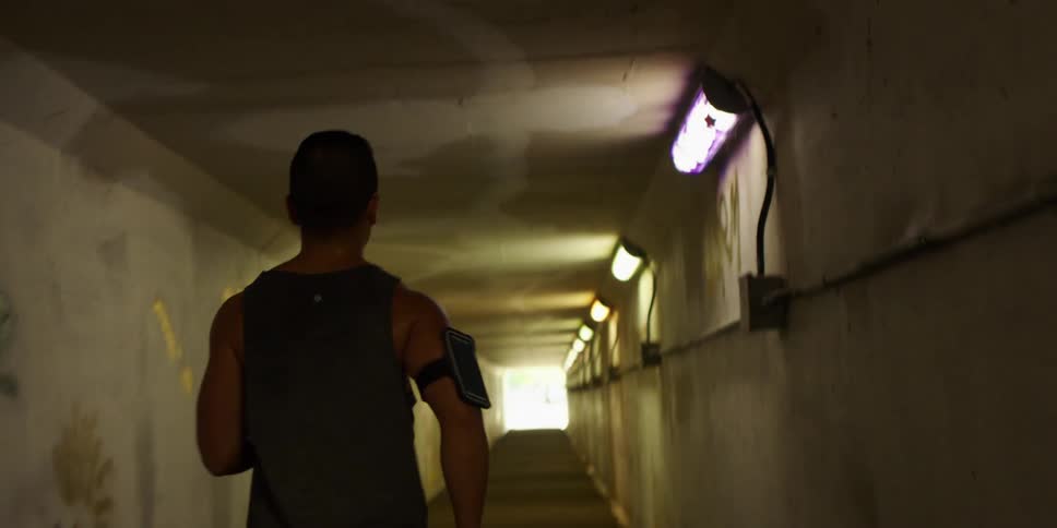 Muscular man wearing an athletic shirt jogging in a tunnel