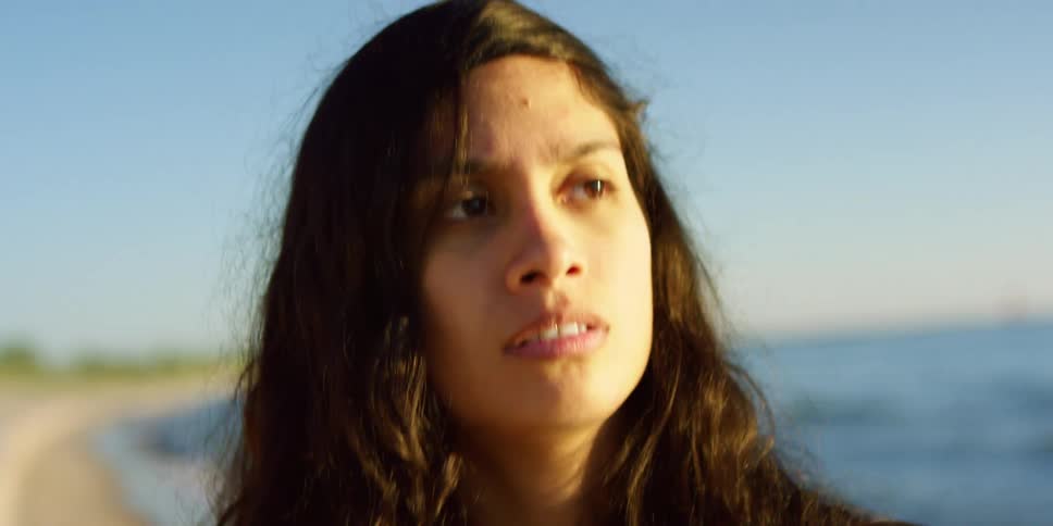 Curly hair brunette girl walks along the beach by the sea