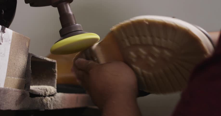 A cobbler grinding the sole of a boot