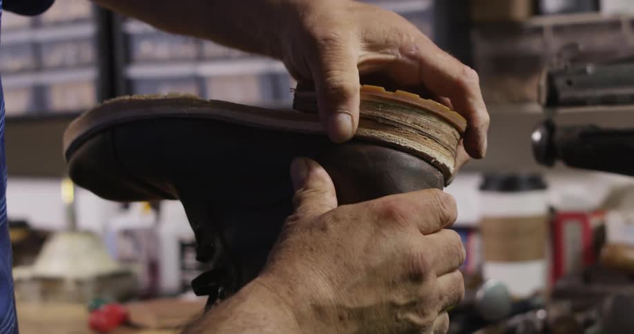 A man fits the heel on a boot he is repairing