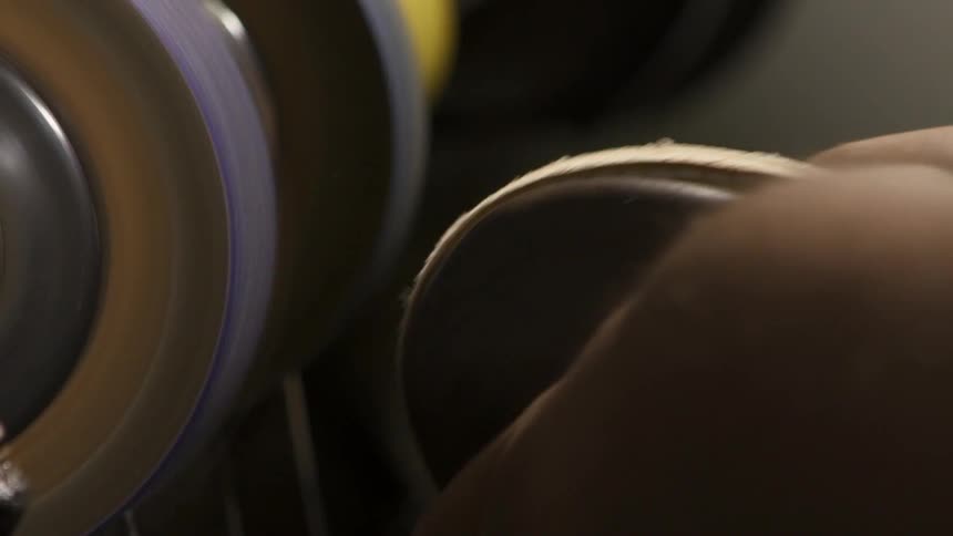 A man using a machine to smooth the sole of a shoe