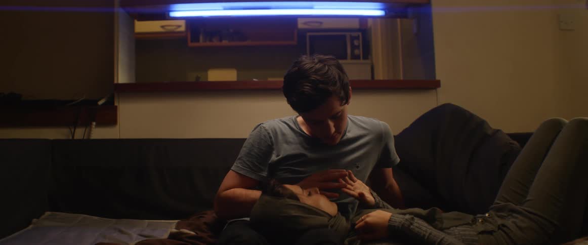Woman lays her head on a mans lap as they touch their hands together
