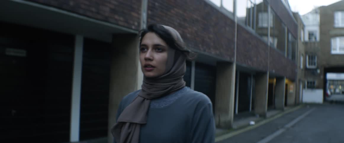 Woman wearing a hijab uses a skateboard on the street of a town