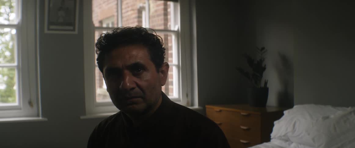 A man sits on his bed in the bedroom