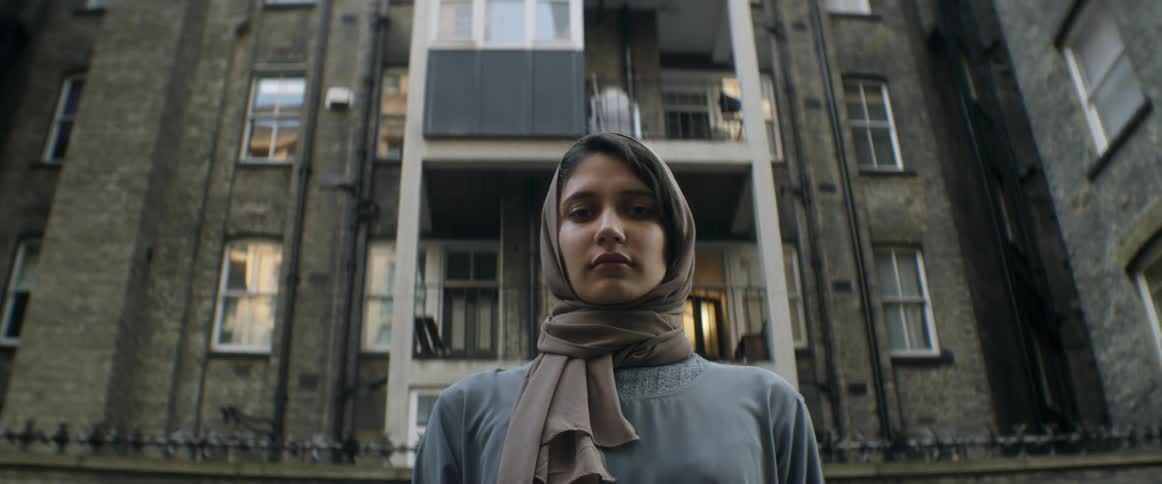 A woman is standing outdoors by a building