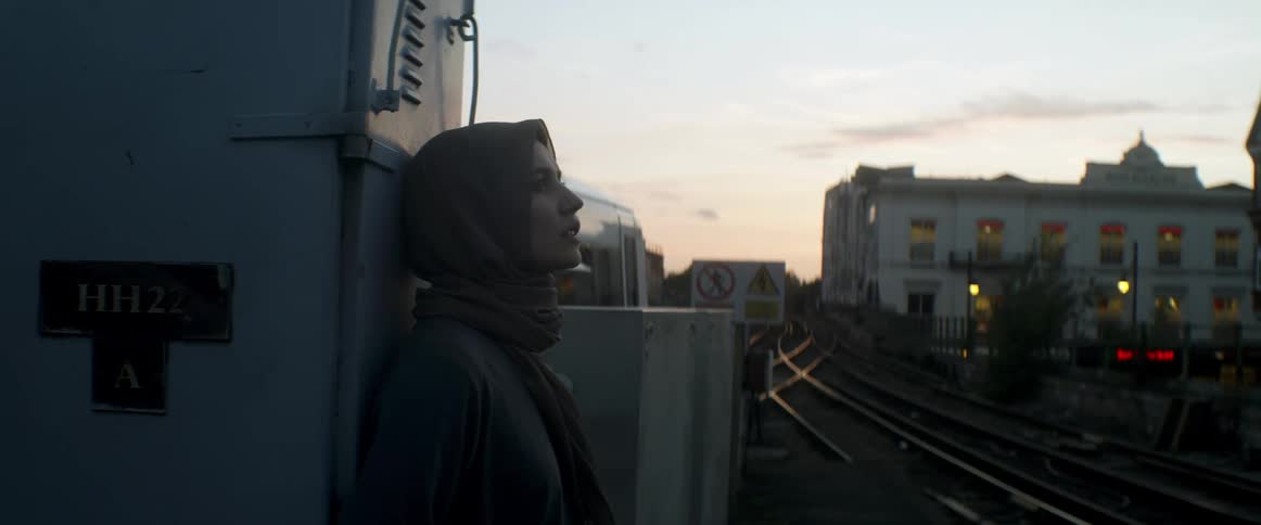 A woman is standing outdoors in a city at dusk