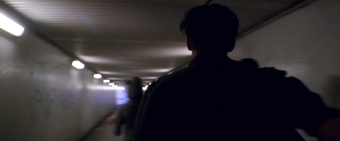 Three teenagers laugh as they run down a hall