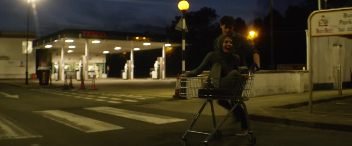 Two teenagers ride a car down the empty street
