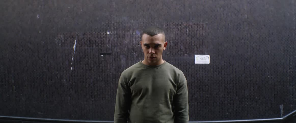 A man looking up with a black background with a white sticker