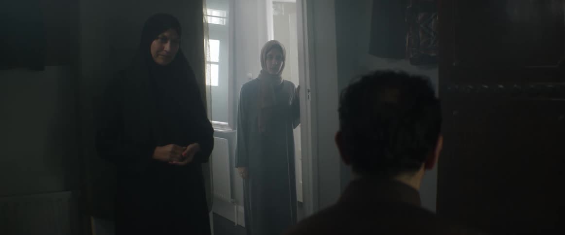 A woman talks to her son in his bedroom as his sister stands in the doorway