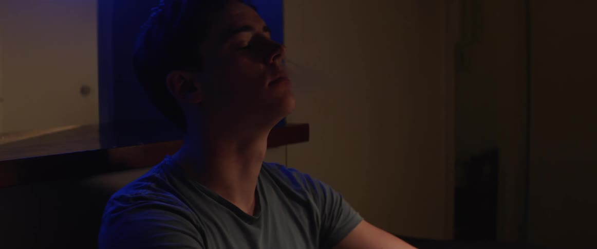 A teenager sitting at home lights a cigarette and starts to smoke