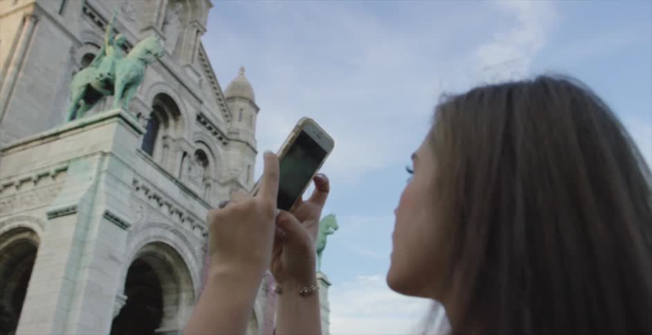 A woman uses a phone to photograph a building