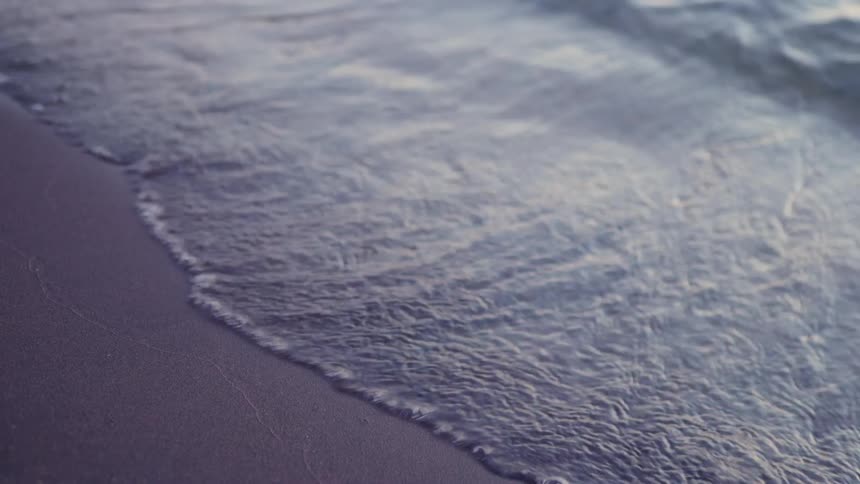 Waves come ashore on a sandy beach