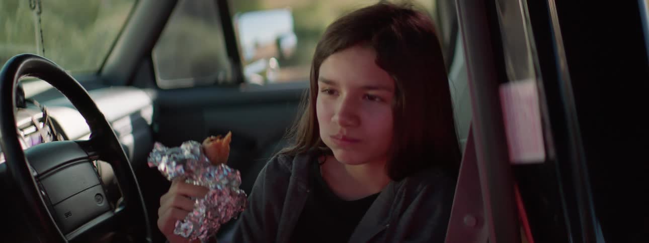 A child is eating food while sitting in a car
