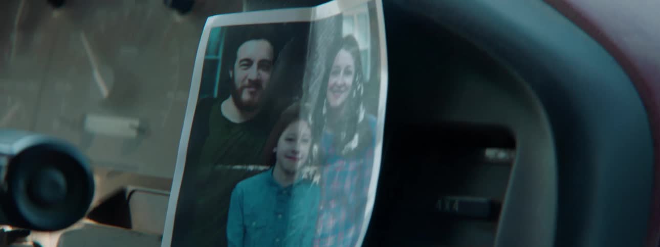 A person drives with a family photo on the dashboard
