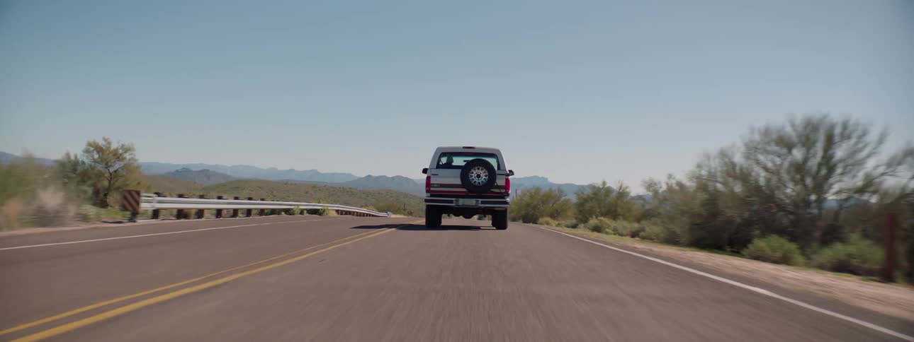 A car travels on a rural road on a clear day