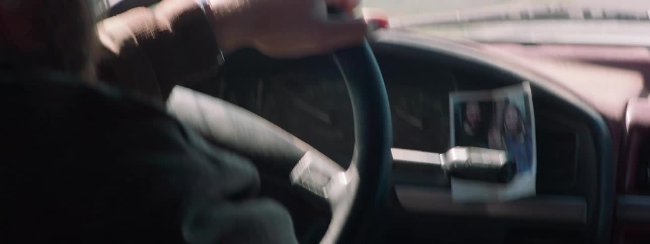 Man with beard and a cap drives a car and takes a mobile phone from his pocket
