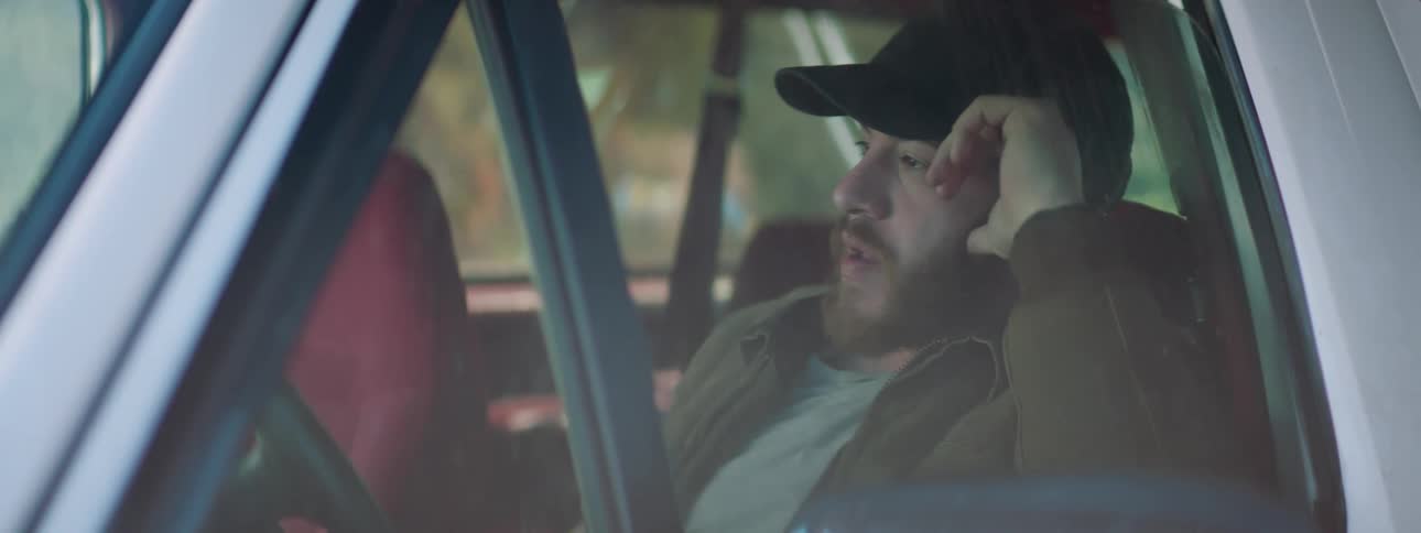 Man with beard and a cap sitting in a car has a sudden outburst of anger and sees someone and gets out of the car