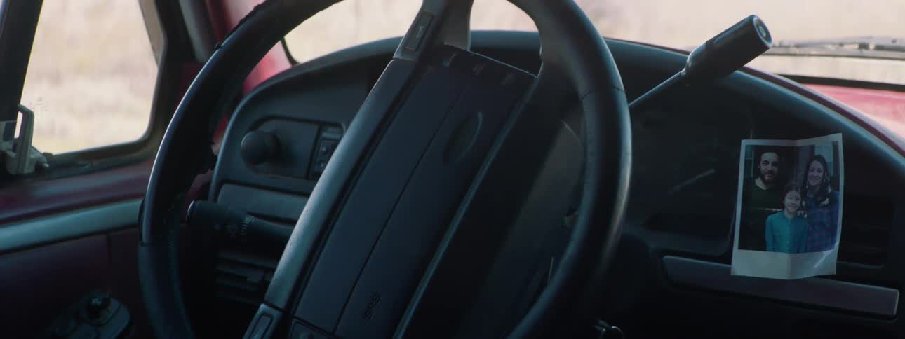 A man climbs in to his truck with a picture on the dashboard