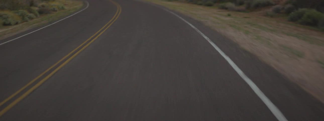 A car travels on a rural road at sunset