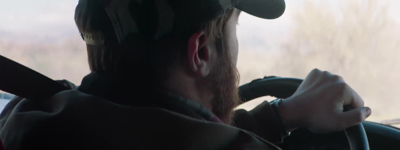 A man changes the radio station while driving a car