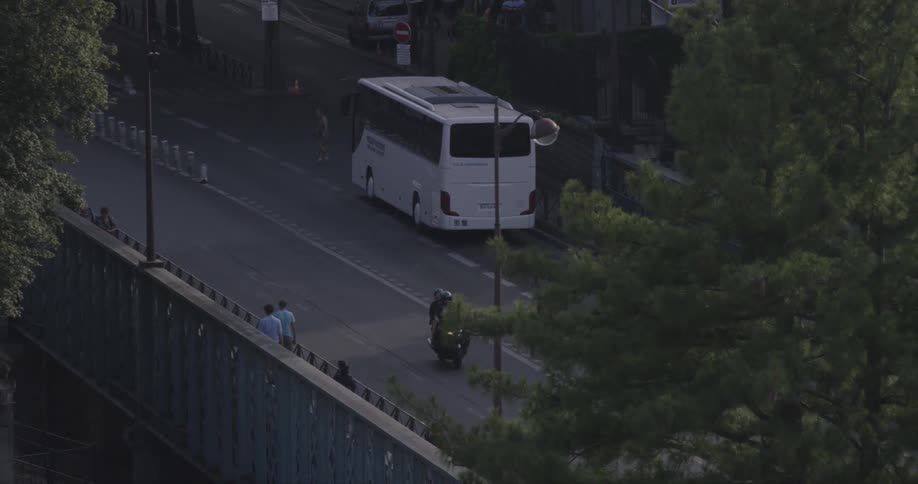 A motorcycle is moving down the street below as people walk nearby