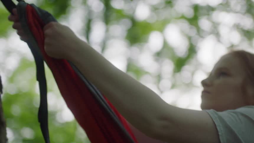 Young girl attaches a hammock to a tree