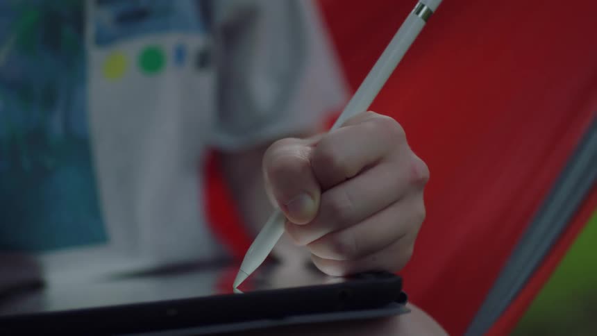 A child uses a stylus to write on a tablet