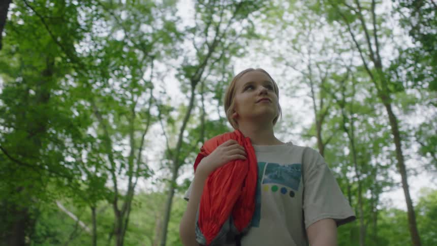 Woman walks among trees in park away from parking lot