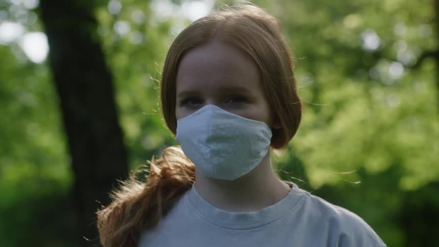 A girl is standing outdoors in a wooded area
