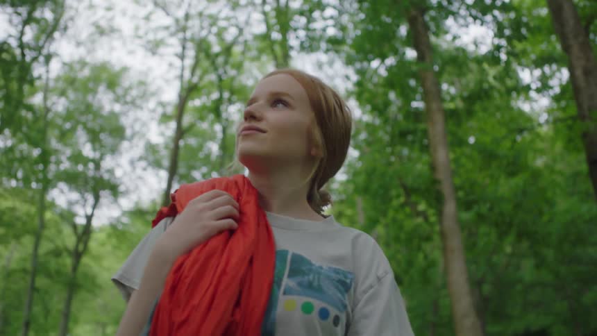 Blonde young woman slowly walks through a forest at day