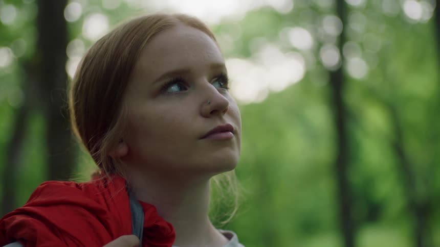 A young female standing in the woods looking around