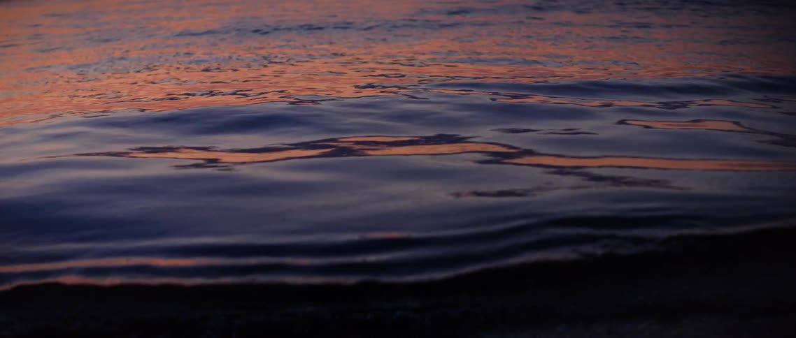 The water is reflecting the setting sun
